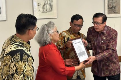 Menkumham Yasonna H Laoly (kanan) disaksikan Menkopolhukam Mahfud MD secara simbolis menyerahkan dokumem kepada Sri Budiarti saat pertemuan dengan eks MAHID.