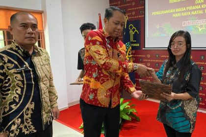 Kadiv Pemasyarakatan Kanwil Kemenkumham Jatim Asep Sutandar menyerahkan remisi Natal kepada salah satu penghuni lapas yang beragama Kristen.