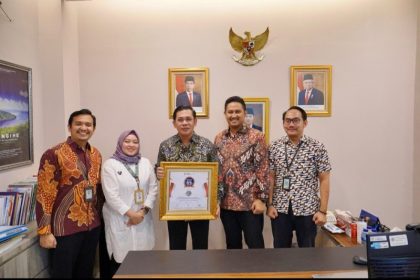 Kepala Biro Hubungan Masyarakat (Humas) Kementerian ATR/BPN, Harison Mocodompis bersama tim kehumasan menunjukkan penghargaan.