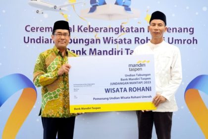 Direktur Bisnis Bank Mandiri Taspen, Maswar Purnama (kiri) menyerahkan giant check kepada perwakilan Pemenang Undian Wisata Rohani Umroh di Jakarta