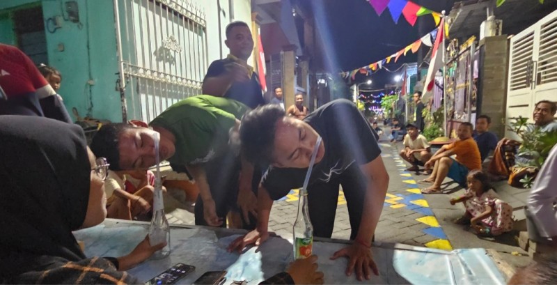 Anak-anak muda yang tergabung dalam karang taruna mempraktekkan lomba ambil pipet dengan hidung sebelum dilombakan. 