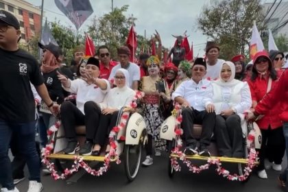 Eri Cahyadi dan Armuji didampingi istri masing-masing menaiki becak menuju kantor KPU Surabaya dengan iring-iringan kirab budaya.