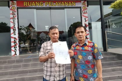 Suyitno (kiri) didampingi kuasa hukumnya menunjukkan bukti laporan polisi di Mapolrestabes Surabaya.