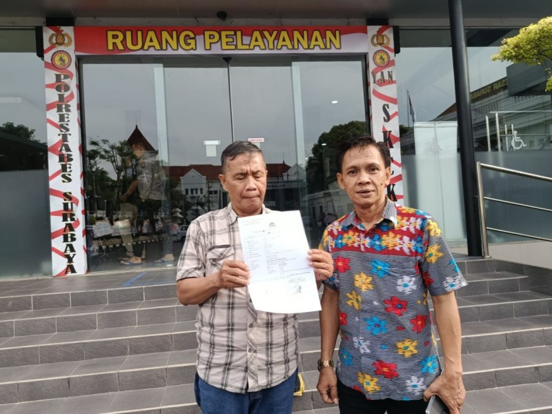 Suyitno (kiri) didampingi kuasa hukumnya menunjukkan bukti laporan polisi di Mapolrestabes Surabaya.