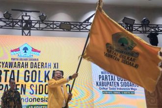 Adam Rusydi, S.Pd., M.Pd., mengibarkan bendera Golkar setelah terpilih kembali untuk kedua kalinya memimpin Partai Golkar di Kabupaten Sidoarjo.