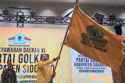 Adam Rusydi, S.Pd., M.Pd., mengibarkan bendera Golkar setelah terpilih kembali untuk kedua kalinya memimpin Partai Golkar di Kabupaten Sidoarjo.