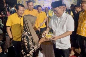 Wakil Ketua DPP Partai Golkar Adies Kadir memberikan potongan nasi tumpeng kepada warga disaksikan Ketua DPD Golkar Sidoarjo, Adam Rusydi dan anggota DPRD lainnya.