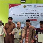 Siswanto, S.H., M.M., Ketua Adjudikasi Tim 3 PTSL, menyerahkan sertifikat PTSL kepada warga sekitar.