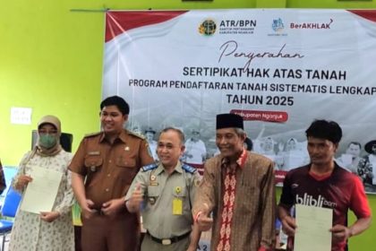 Siswanto, S.H., M.M., Ketua Adjudikasi Tim 3 PTSL, menyerahkan sertifikat PTSL kepada warga sekitar.