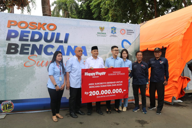 Judystira Setyadji, Direktur Pemasaran Happy Puppy Group, menyerahkan bantuan uang tunai kepada Wali Kota Surabaya Eri Cahyadi di Posko Peduli Bencana Taman Surya, Balai Kota Surabaya, Jumat, 12 Desember 2025.