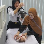 Petugas imigrasi mengambil gambar seorang balita untuk foto paspor.