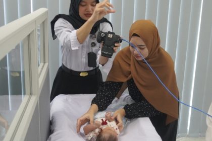 Petugas imigrasi mengambil gambar seorang balita untuk foto paspor.