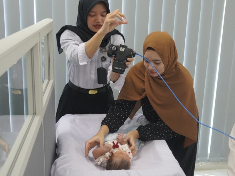 Petugas imigrasi mengambil gambar seorang balita untuk foto paspor.