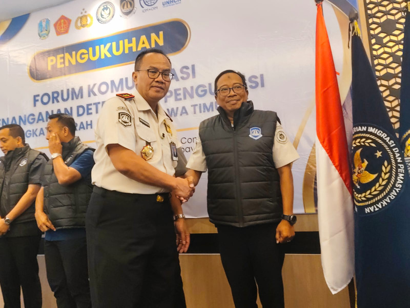 Kepala Kanwil Direktorat Jenderal Imigrasi Jatim, Novianto Sulastono, menyematkan rompi kepada salah satu anggota Forkopdensi dalan giat FGD di hotel Surabaya.