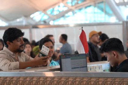 Petugas imigrasi Indonesia melayani pemeriksaan paspor milik warga negara asing.