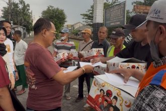Ketua DPC PDIP Surabaya Armuji, membagikan bingkisan parcel kepada para relawan penjaga pintu palang kereta api.